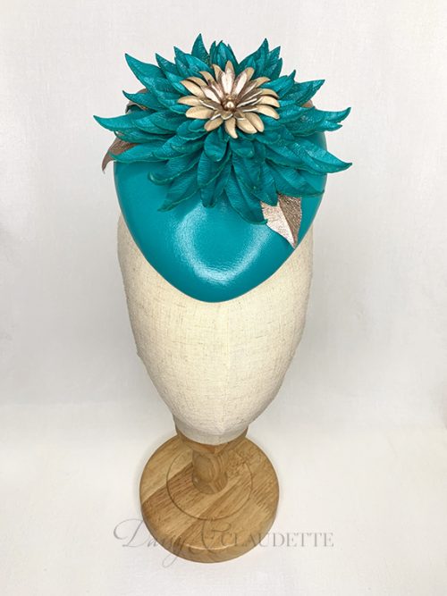 Deep teal leather oval beret with a very large statement leather flower of the same colour, with contrasting centre of nude and vintage gold petals and a gold pearl.