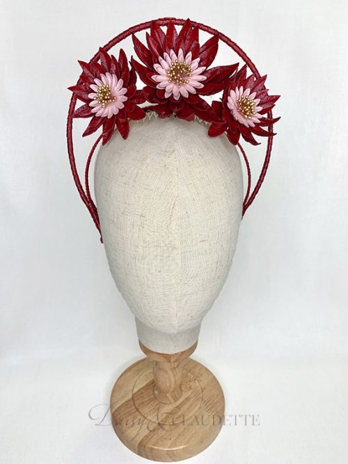 Large red leather flowers with pink centres and gold stamens fitted on a headband finished with red leather binding and features a high halo.