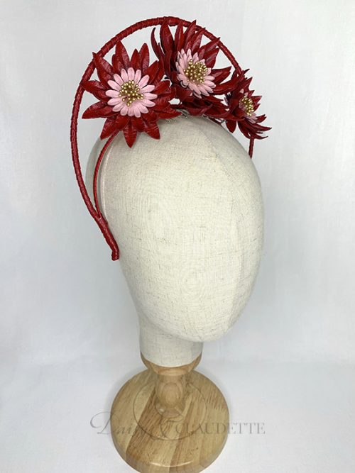 Large red leather flowers with pink centres and gold stamens fitted on a headband finished with red leather binding and features a high halo.