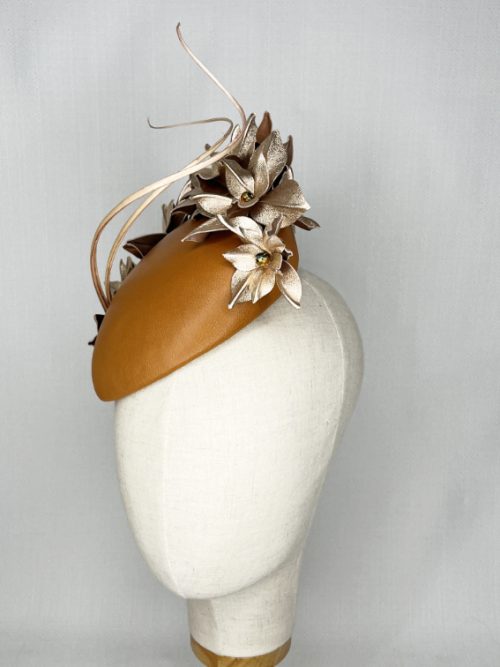 Tan leather beret headpiece with metallic flowers and curled feather quills