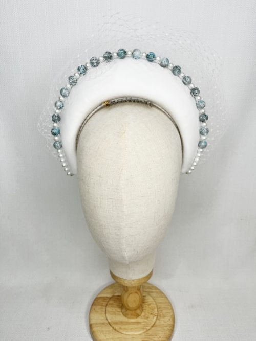 White leather headband trimmed with pearl and blue toned beads and white veiling.