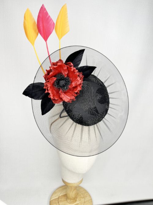 Mannequin wearing a large headpiece with a veil brim, leather flower and feather trims.