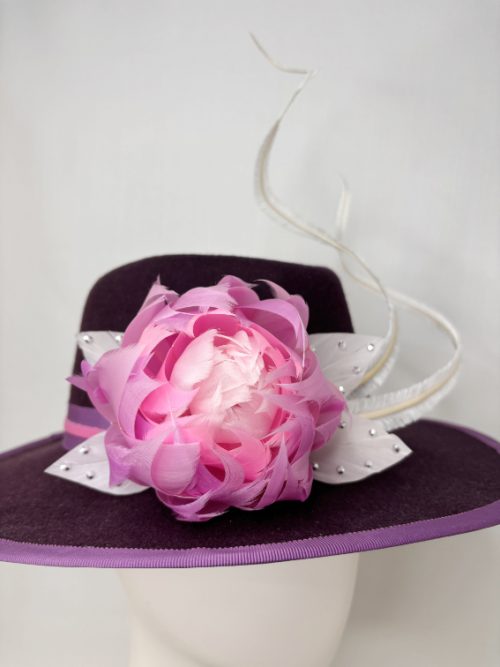 A mennequin wearing a felt hat with a feather flower feature.