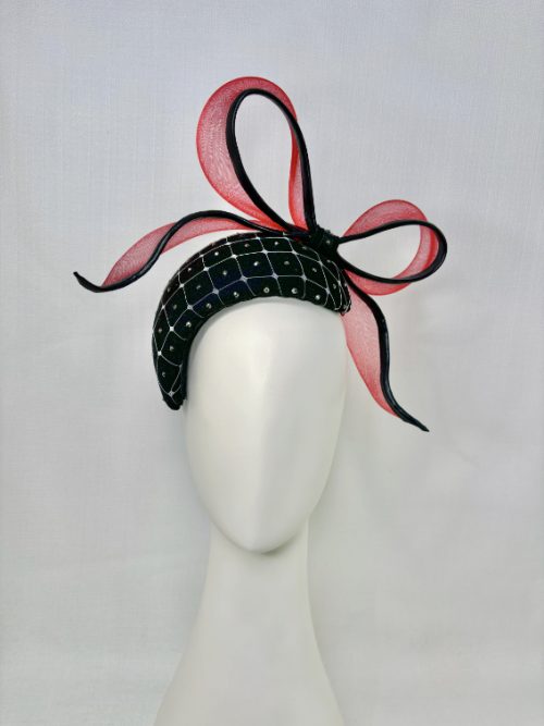 Black felt fascinator with a red bow on a mannequin.