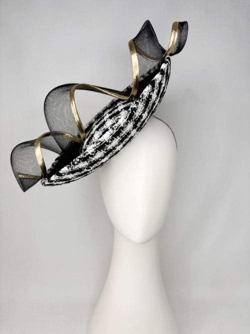 Black and white bouclé satellite dish shaped hat worn on the side by a mannequin.